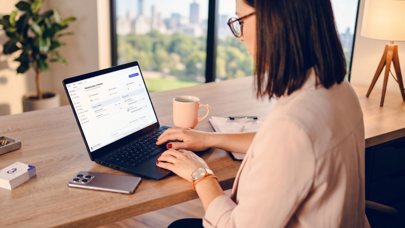 Frau, die die G-P -Plattform auf ihrem Laptop an einem hellen Bürotisch neben einem Fenster benutzt​​ 