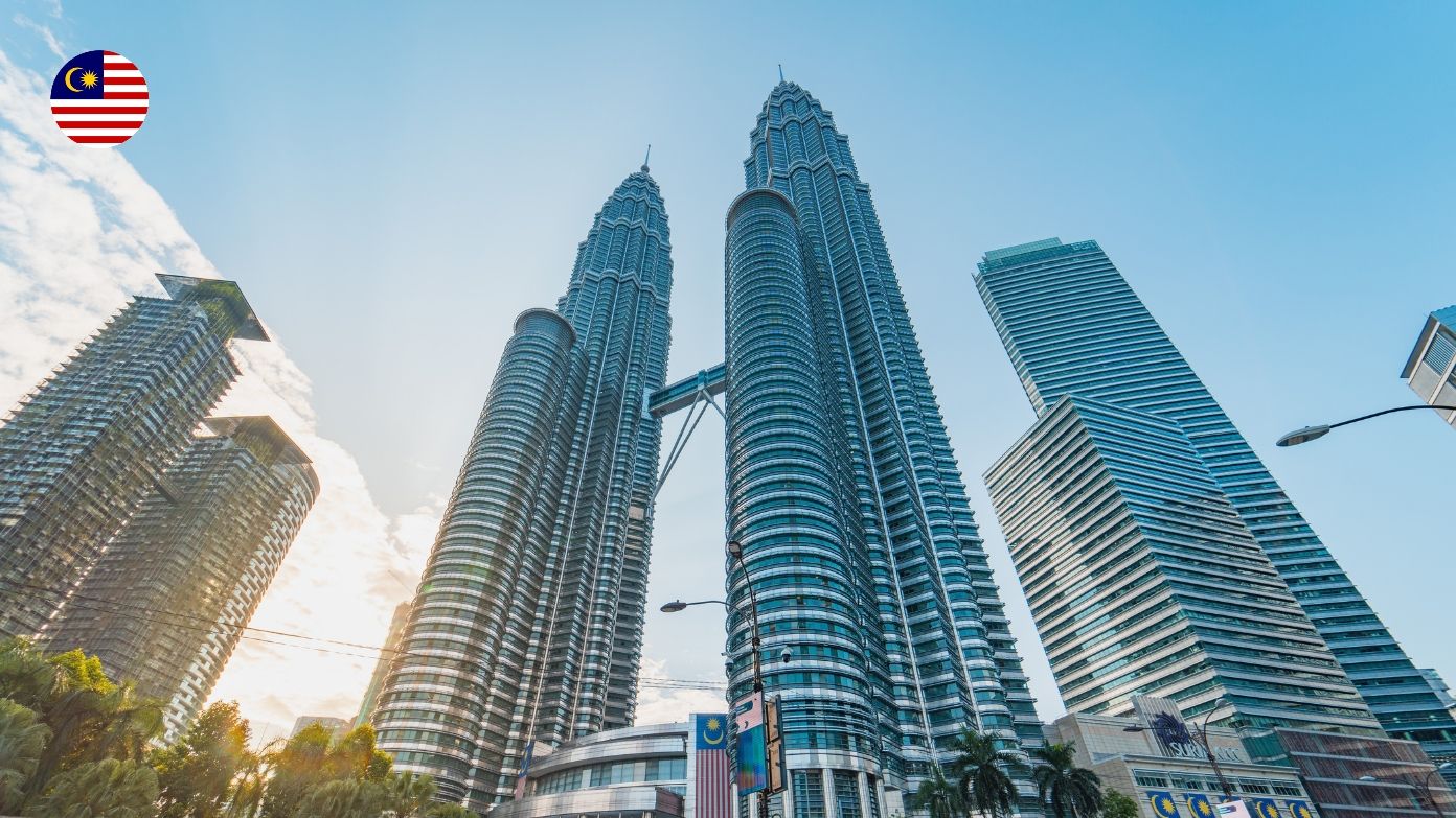 Laag uitzicht met uitzicht op de iconische Petronas Twin Towers in Kuala Lumpur, Maleisië onder een heldere lucht.​​ 