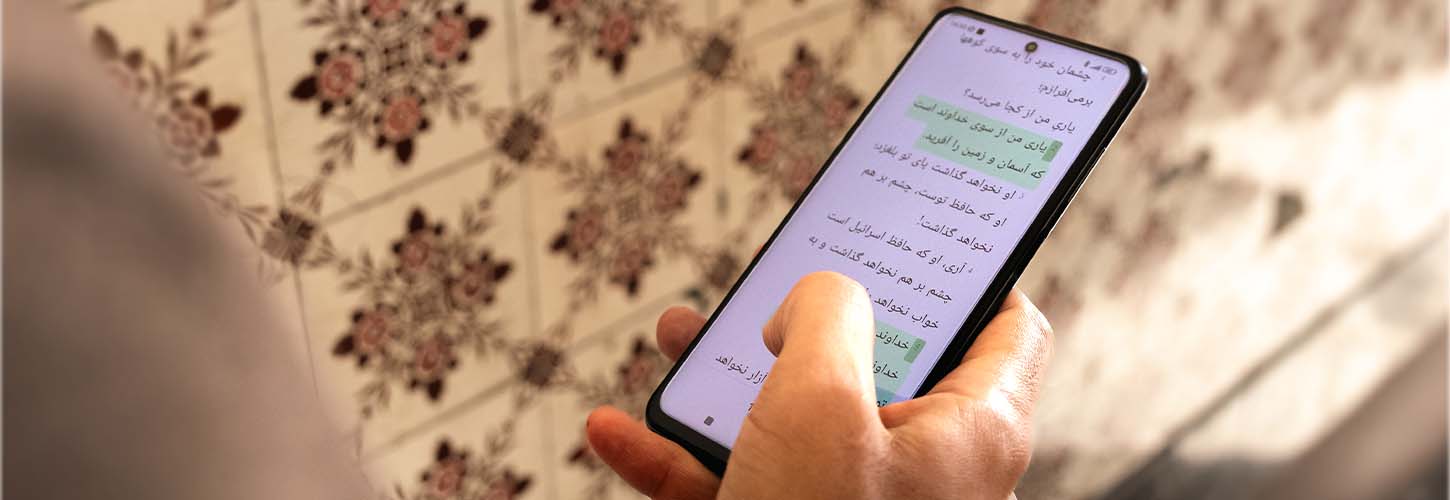 Hands holding a phone displaying the Bible App