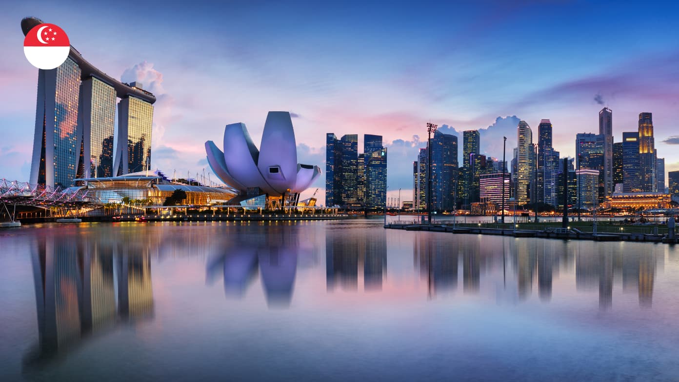 Singaporese skyline met het lotusvormige ArtScience Museum weerspiegeld in kalm water bij zonsondergang​​ 